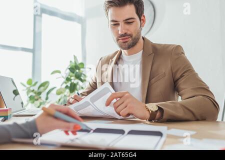 Selektive Fokussierung von ux-Designern, die mit dem Drahtmodelllayout mobiler Anwendungen am Tisch arbeiten Stockfoto