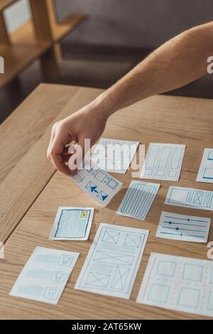 Zugeschnittene Ansicht des ux-Entwicklers, der mit Anwendungsskizzen auf dem Tisch arbeitet Stockfoto
