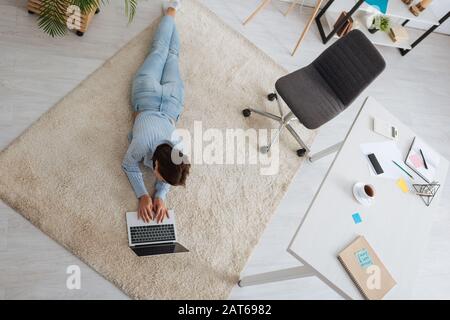 Overhead-Ansicht von Bloggern, die auf Teppich liegen und Laptops verwenden Stockfoto