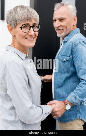 Reifer Mann, der lächelnde Frau betrachtet und in ein neues Haus eindringt Stockfoto