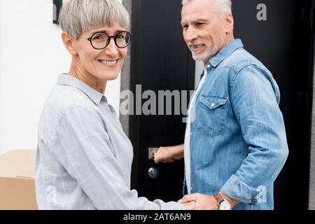 Reifer Mann, der lächelnde Frau betrachtet und in ein neues Haus eindringt Stockfoto