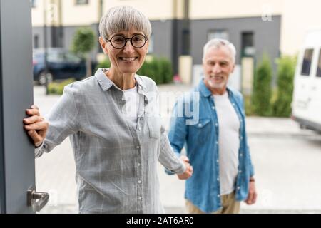 Selektiver Fokus der lächelnden Frau, die mit dem Mann die Hände hält und in ein neues Haus eindringt Stockfoto