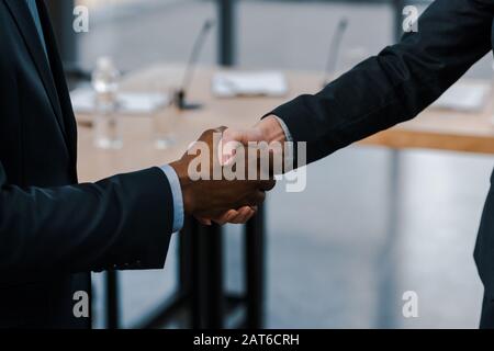 Beschnittenes Bild der Geschäftsfrau, die mit dem afroamerikanischen Diplomaten die Hände schüttelt Stockfoto