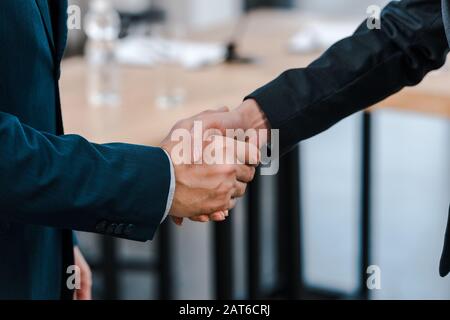 Beschnittenes Bild der Geschäftsfrau, die mit dem Geschäftsmann die Hände schüttelt Stockfoto