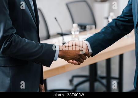 Beschnittenes Bild von Geschäftsleuten, die mit dem afroamerikanischen Diplomaten die Hände schütteln Stockfoto