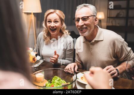 Selektives konzentrieren des lächelnden Mannes und der Frau, die während des Abendessens mit einem Freund sprechen Stockfoto