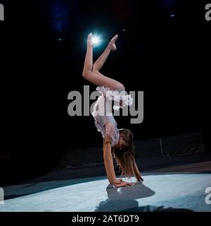 Mädchen im Kostüm, das Handstand macht, während sie in der Arena des Zirkus auftreten Stockfoto