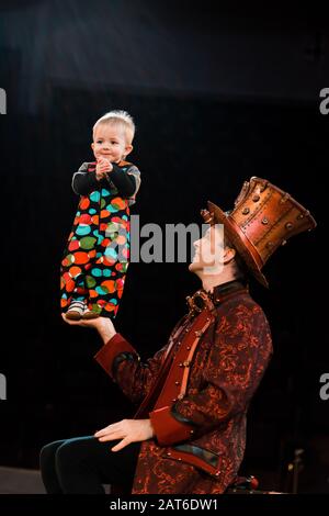 Glücklicher Mann, der süße akrobatische Kleinkinder in der Hand hält Stockfoto