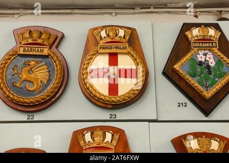 Ausstellung von vielen Abzeichen der Royal Navy Schiffe im Nothe Fort Museum, Weymouth, Dorset, UK Stockfoto