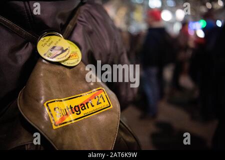 Stuttgart, Deutschland. Januar 2020. Ein Teilnehmer der 499th Montagsdemonstration gegen das Bahnprojekt Stuttgart 21 trägt bei einer Kundgebung auf dem Schlossplatz einen Rucksack mit einem Protestaufkleber auf dem Rücken. Zehn Jahre nach der ersten Montagsdemonstration gegen 'Stuttgart 21' fordern die Gegner des Bahnbauprojekts zum 500. Mal Protest gegen den U-Bahnhof. (Zu dpa 'Montage-Demonstration gegen Stuttgart 21 nur einen Tag nach Baujahr') Credit: Tom Weller / dpa / Alamy Live News Stockfoto