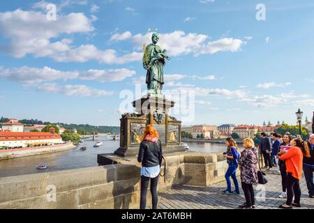 Touristen an der Statue des heiligen Johannes von Nepomuk über den Bronzeplaketten dachten, dass sie beim Rubbbben Glück bringen sollten, auf der Karlsbrücke in Prag, Tschechien. Stockfoto