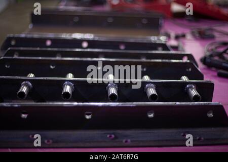 Ein Teil der Treppe aus Metall. Detail aus Rohren geschweißt und von einer Schleifmaschine geschnitten. Eine gebürstete Stahlkonstruktion auf einem Tisch in einer Werkstatt. Das Metallprofil Stockfoto