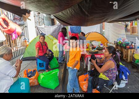 Oaxaca de Juarez, Oaxaca, Mexiko. Januar 2020. Einige der 209 Familien, die im November 2019 aus ihren Häusern vertrieben wurden, protestieren, indem sie auf einer Hauptstraße in der Landeshauptstadt Oaxaca campen. Sie sagen, dass sie legalen Besitz des Landes hatten, in dem sie viele Jahre in der Stadt Santa Cruz Xoxocotlan gelebt haben, aber von einer paramilitärischen Gruppe, die für Immobilieninteressen arbeitet, gewaltsam vertrieben wurden. Kredit: Jim West/Alamy Live News Stockfoto