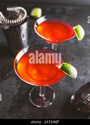 Roter Cocktail mit Limette im Martini-Glas auf dem Tisch. Stockfoto