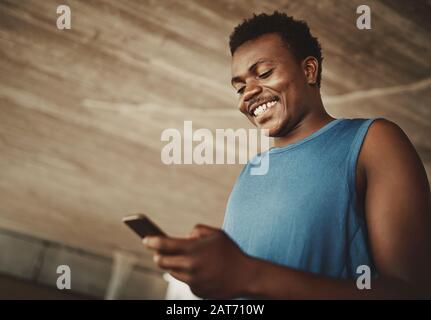 Die niedrige Ansicht eines männlichen Läufers, der Nachrichten auf dem Mobiltelefon im Freien versendet Stockfoto