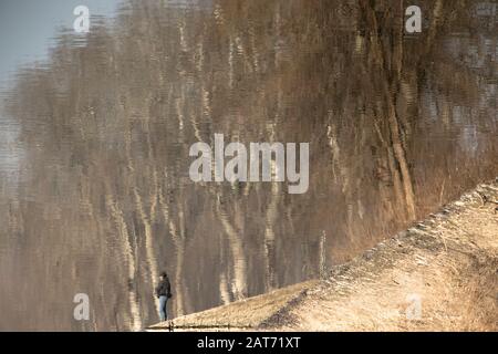 Verschwommene Silhouettenreflexion einer Person und eines Waldes in Flusswässern an einem sonnigen Tag Stockfoto