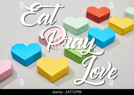 Dekorative bunte Herzen auf grauem Hintergrund mit Essen, Beten, Liebesillustration Stockfoto