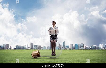 Frau mit offenem Buch sitzen auf großen Glühbirne Stockfoto