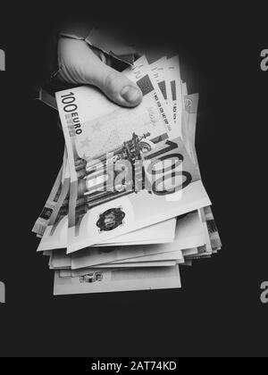 Hand erscheint Euroraumwährung im Loch von zerrissenem Papier, das Konzept des Geldgeschenks, der Überraschung, des Gewinns, der Behandlungsgebühren, der Bestechung, der illegalen Operation. Stockfoto