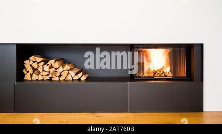 Moderner Kamin im Wohnzimmer mit Platz für die Lagerung von Holz Stockfoto