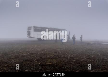 Großer weißer Bus und eine Gruppe von Menschen in der Nähe Im nebligen Wetter in Island Stockfoto