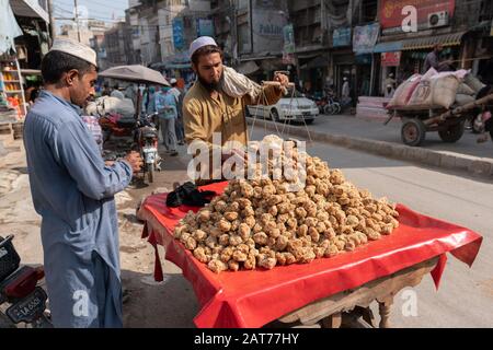 Paschtun man verkauft Jaggery ('Gur') aus Zuckerrohr auf den Straßen von Peschawar, Pakistan Stockfoto