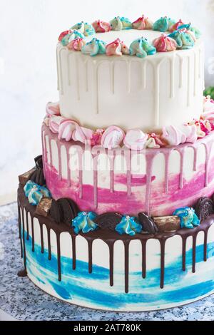 Dreifach gestufter Farbkuchen mit farbigen Schmutzflecken aus Schokolade auf hellem Hintergrund. Bild für ein Menü oder einen Süßwarenkatalog, den Hochzeitstorte Stockfoto