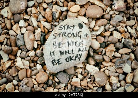 'SBleibe stark, sei nett, es wird okay sein'. Positive Nachricht geschrieben auf Stein am Aldeburgh Beach, Aldeburgh, Suffolk. Stockfoto