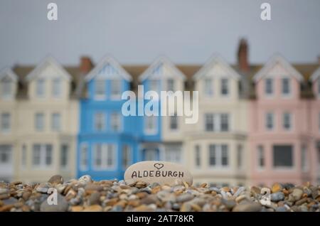 Stein mit "Liebe (Herz) Aldeburgh", mit farbigen Häusern im Hintergrund. Stockfoto