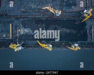 Laden Kohle Anthracite Mining im Hafen auf Cargo tanker Schiff mit Kran Eimer von Zug. Antenne Top View Stockfoto