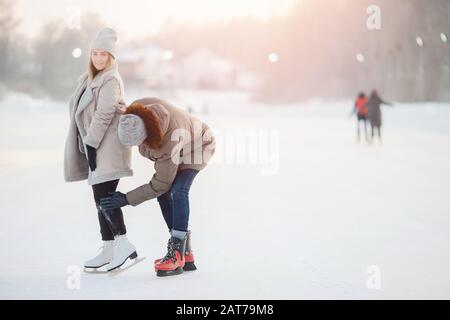 Der Mann hilft und schüttelt Mädchen aus dem Schnee, nachdem er im Winter auf der Eisbahn gefallen ist. Konzeptpflege und Liebe zum Paar Stockfoto