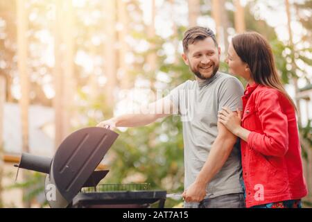 Mann und junge Frau frittieren Fleisch auf dem Grillgrill im Naturgarten Stockfoto