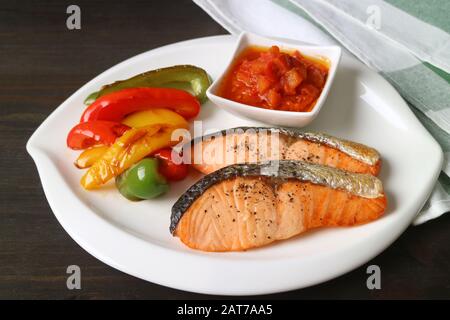 Teller mit hausgemachter Pfanne gebratener Lachssteaks mit bunten gegrillten Paprika Stockfoto