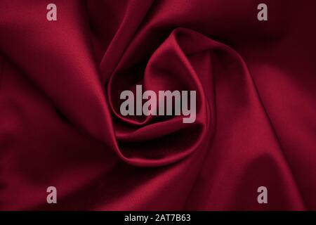 Roter romantischer Stoffhintergrund. Falten von Seide, dunklem Satin, Falten von Textil, natürliches Muster, glänzende Textur von Tuch Stockfoto