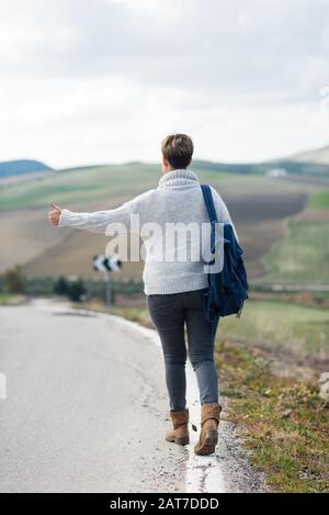 Frau mit Rucksackhitchwandern auf einer einsamen Landstraße. Stockfoto