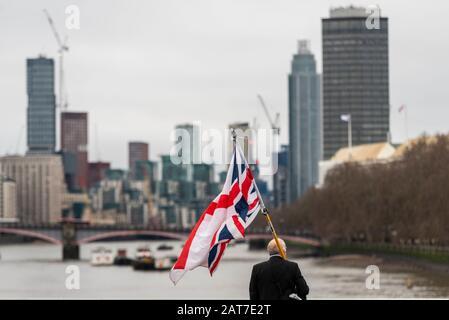 Westminster, London, Großbritannien. Januar 2020. Der Tag ist am Tag, an dem Großbritannien die Europäische Union offiziell verlässt, stumpf und grau. Der Brexit wird am Abend um 23 Uhr mit einer Feier auf dem Parlamentsplatz gefeiert. Ein ranghoher kaukasischer Mann mit England und britischen Flaggen auf der Westminster Bridge Stockfoto