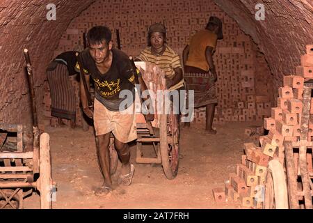 Arbeiter, die Transport, feuerten Ziegelsteine in einem Ringofen einer Ziegelfabrik in der Nähe von Luang Prabang, Laos Stockfoto