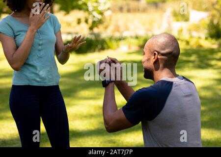 Junger Mann, der Heiratsantrag im Garten macht Stockfoto