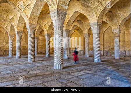 Iranerin, die mit Schabestan-Säulen, Vakil-Moschee, Shiraz, Fars Provinz, Iran durch den Betsaal spazieren geht Stockfoto