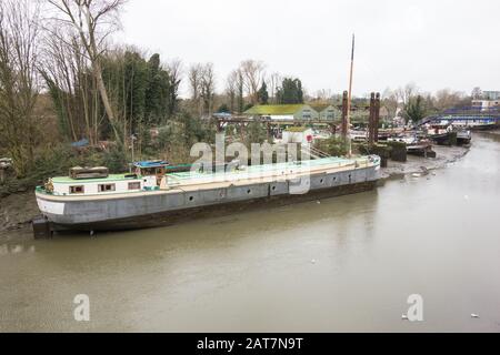 John's Boat Works Ltd,- bunte Hausboote, die auf Lot's Ait an der Themse gegenüber dem Waterman's Arts Center, Brentford, London, Großbritannien repariert werden Stockfoto