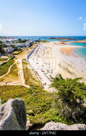 Luftbild über den Strand von Greve Blanche in Tregastel, Bretagne, an einem sonnigen Sommertag mit Menschen zum Sonnenbaden und zum genießen des türkisfarbenen Meeres. Stockfoto