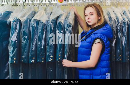 Weibliche Reiniger in Wäsche shop oder textile Reinigung Neben saubere Kleidung in Kleidersäcke Stockfoto