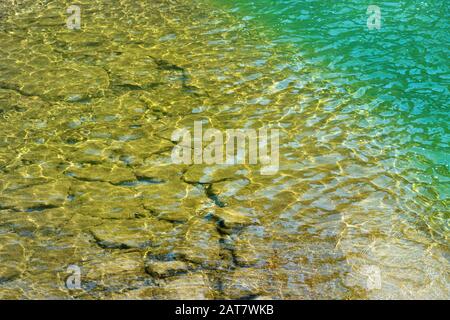 Flaches, schimmerndes Wasser an einem befestigten Ufer Stockfoto