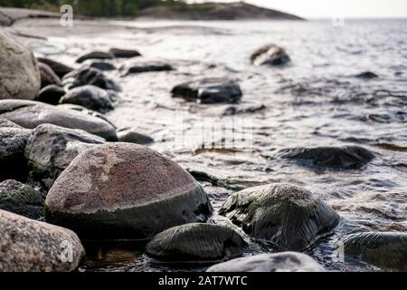 Felsige Küste, vor dem Hintergrund des Meeres mit kleinen Wellen, Felsen und Himmel. Untere Ansicht. Stockfoto