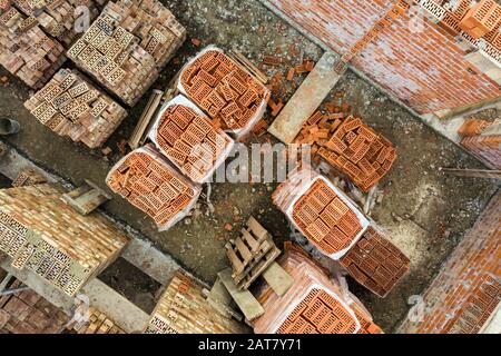 Luftbild der Baustelle für zukünftiges Ziegelhaus, Betonfundament und Stapel gelber Lehmziegel für den Bau. Stockfoto