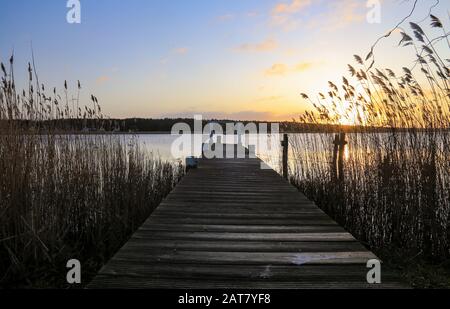 Alter Holzsteg am kleinen schönen Teich bei Sonnenuntergang Stockfoto