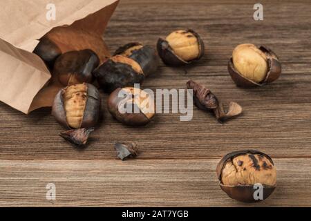 Nahaufnahme von gerösteten Kastanien in einer Papiertüte auf einem Holztisch Stockfoto