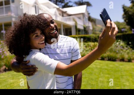 Glückliches junges Paar, das selfie im Garten mitnimmt Stockfoto