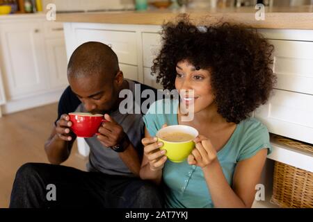 Fröhliches junges Paar sitzt in der Küche Stockfoto