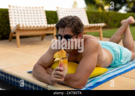 Junge Frau, die sich an einem sonnigen Tag in der Nähe des Schwimmbads erholte Stockfoto